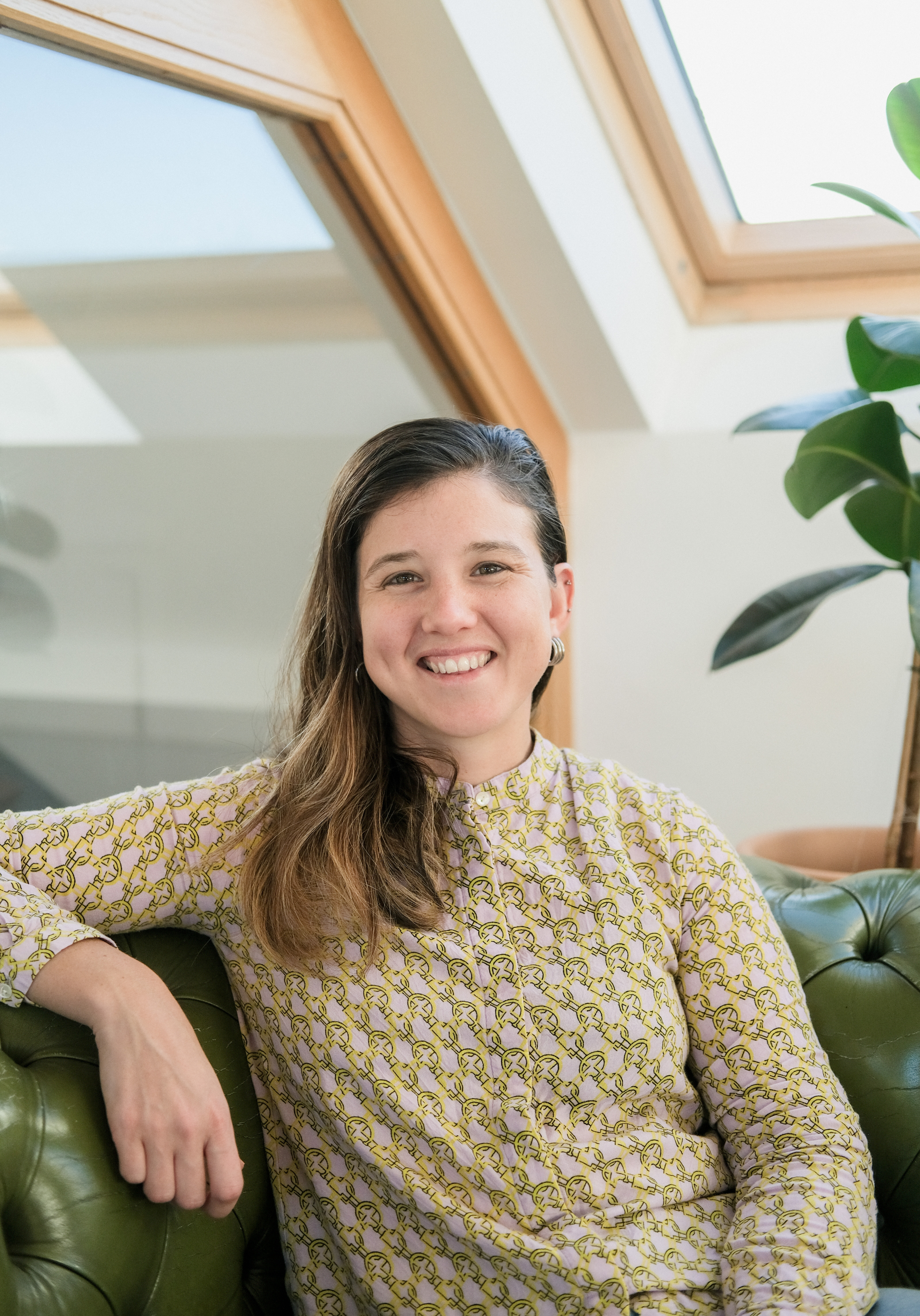 Portrait of a man with brown hair and glasses on a flat gray background.